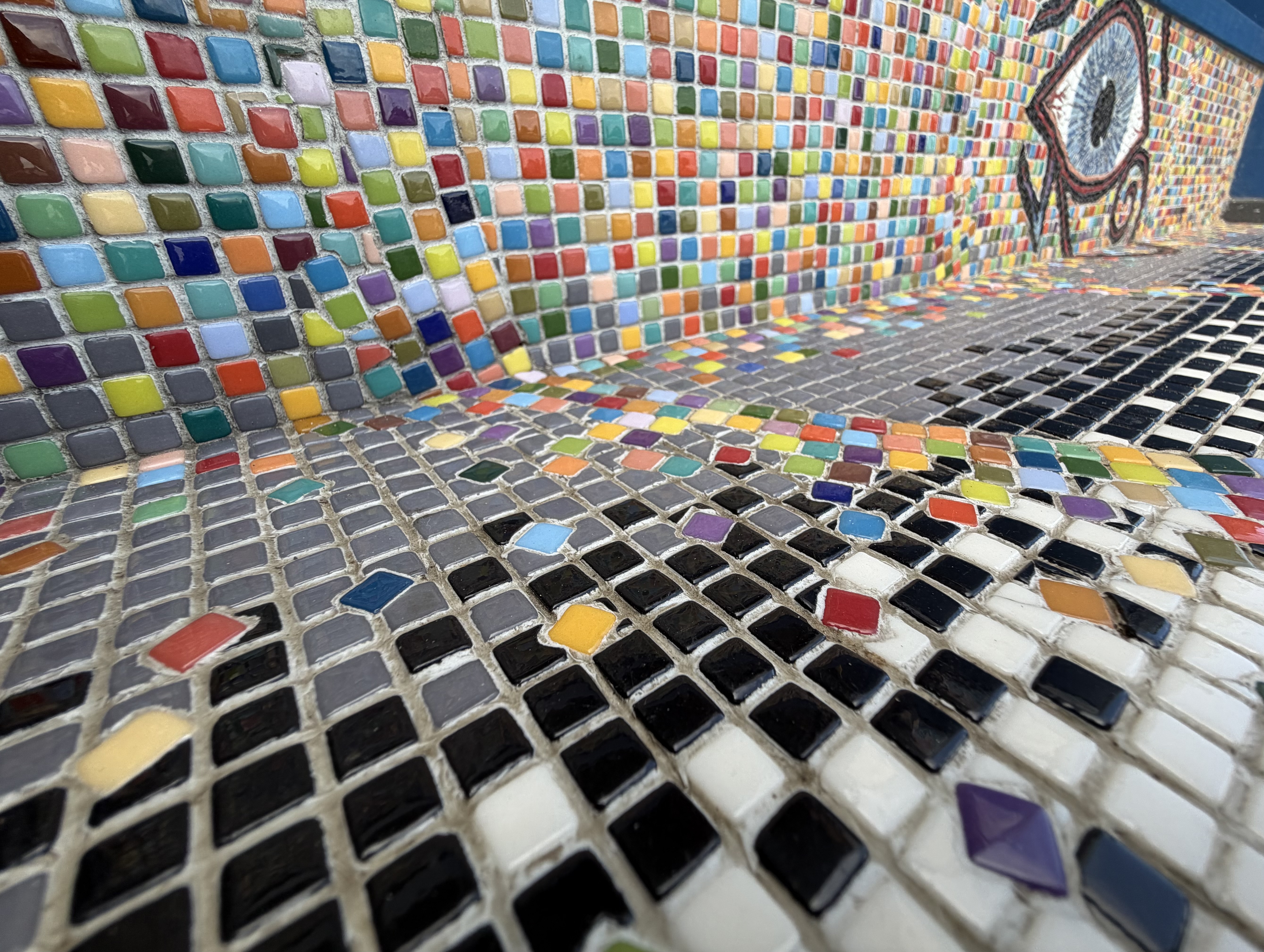 Interior perspective of the mosaic bench, rainbow tile walls leading toward the Eye of Horus in the distance