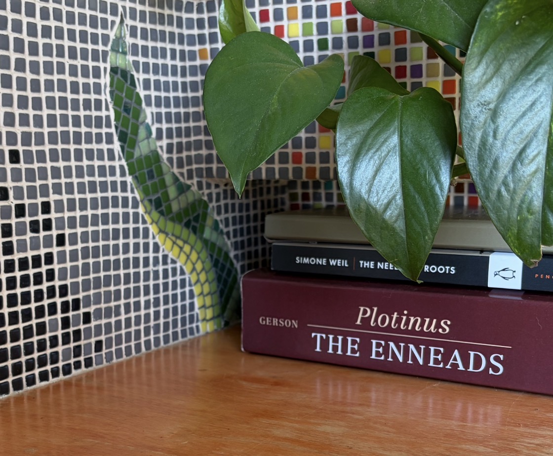 Detail of a mosaic serpent, apple, and branch on a golden tessellated ground, beside a real houseplant