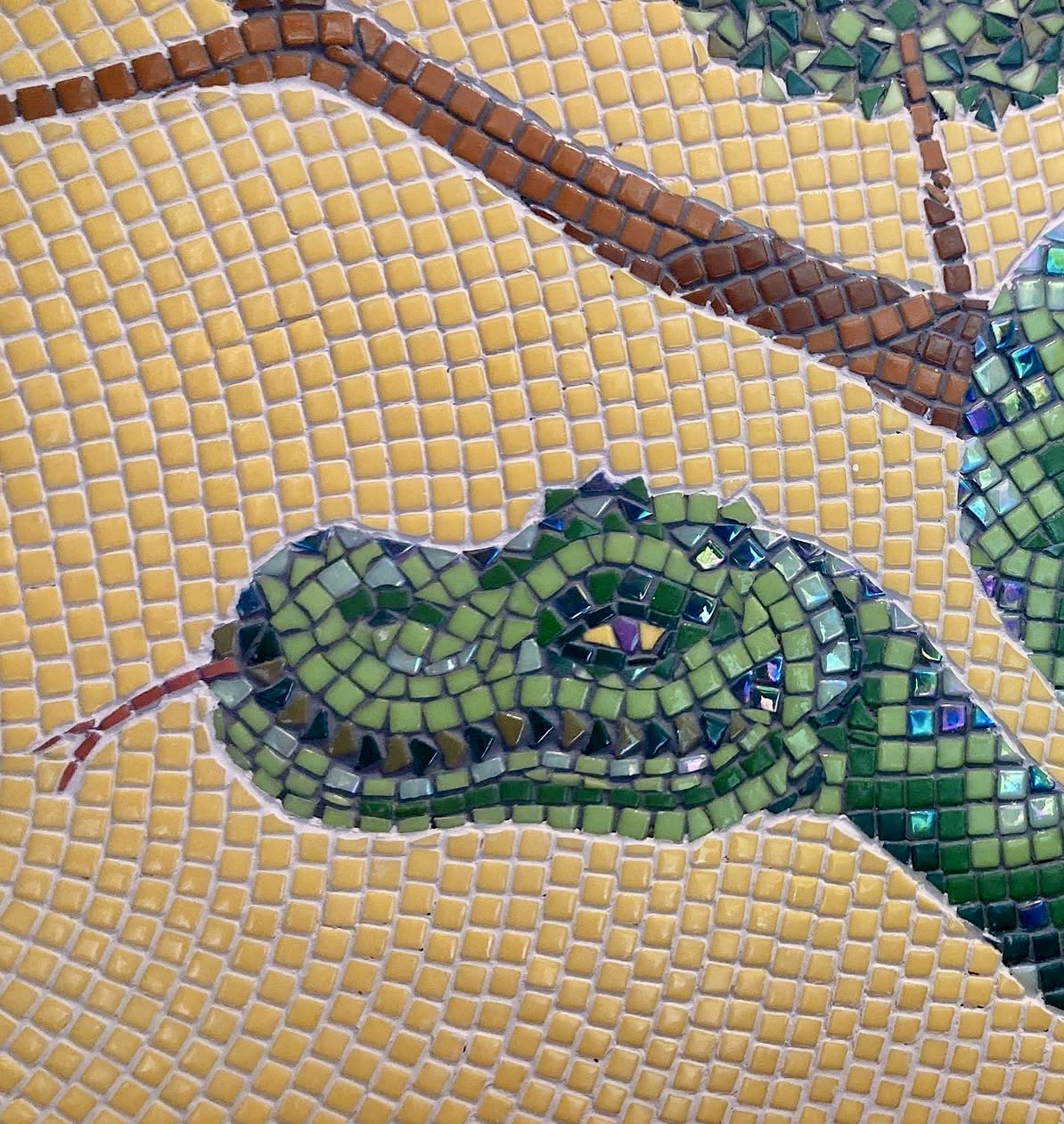 Close-up detail of the mosaic serpent's head, coiled with iridescent green and dark glass tesserae against a golden tessellated ground