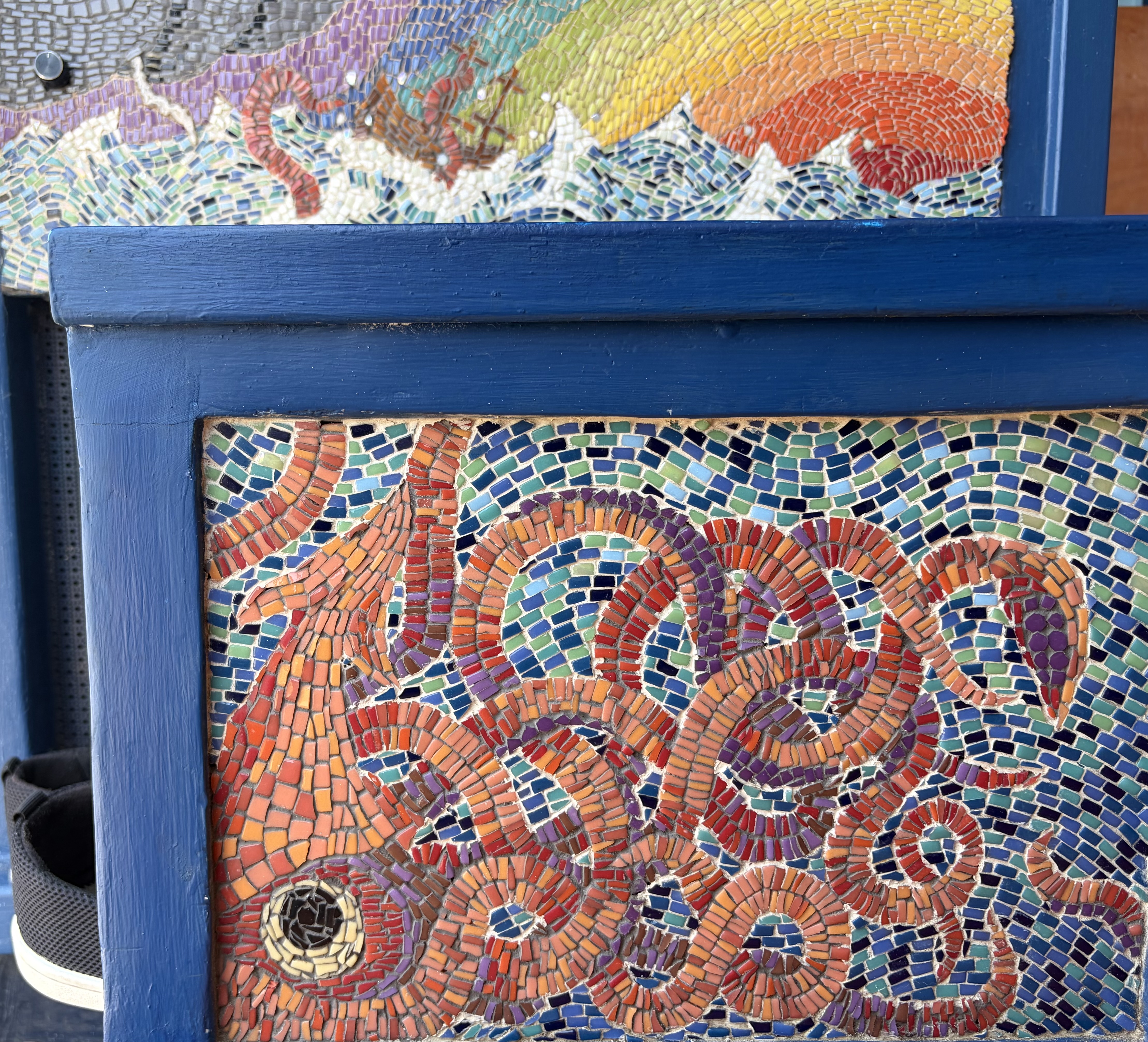 Depth mosaic detail, interlocking spiral tesserae in warm reds, oranges, and purples on a blue-green ground