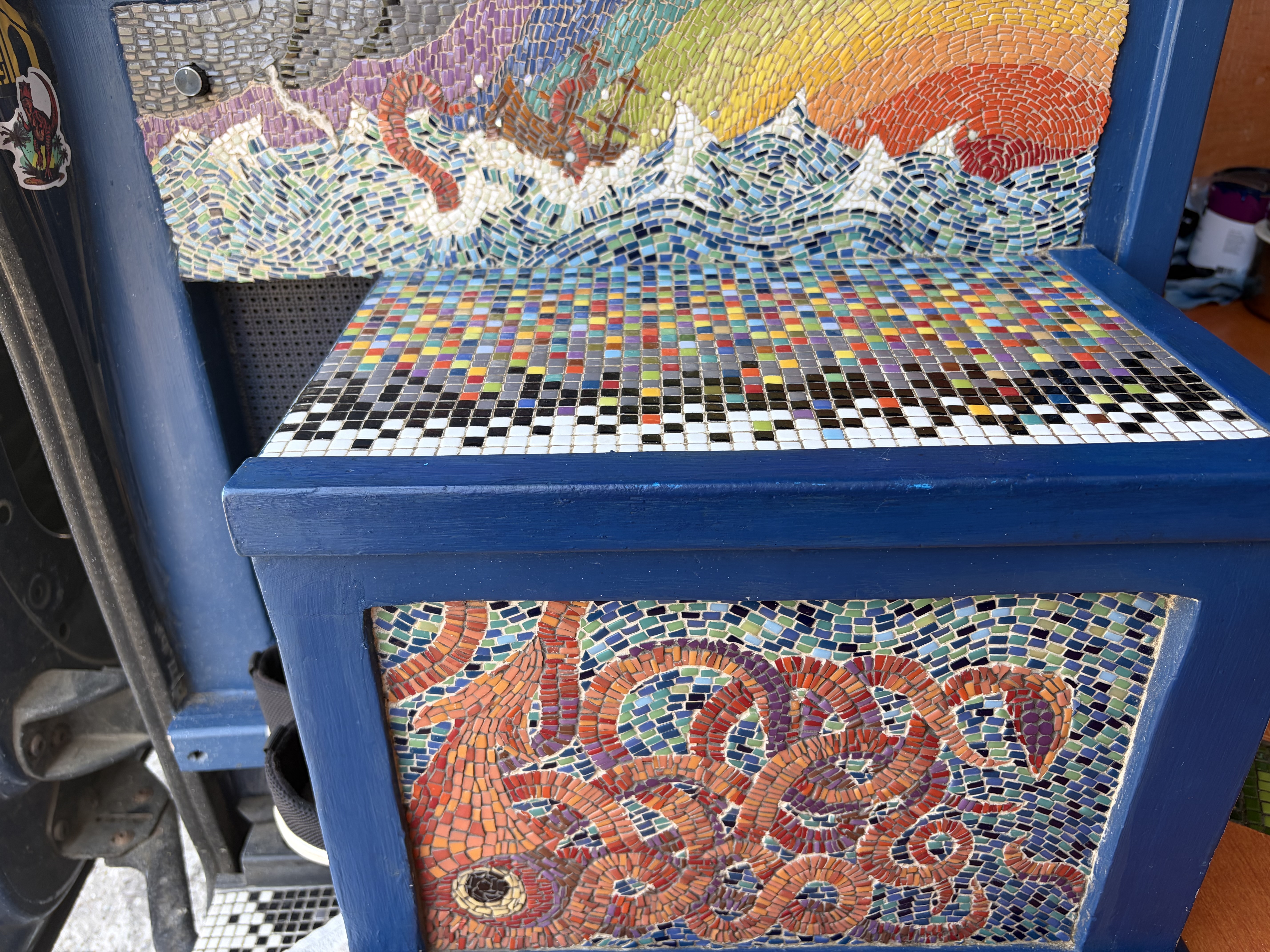 Depth mosaic built into a bench, shown with a rainbow wave-and-ship scene above