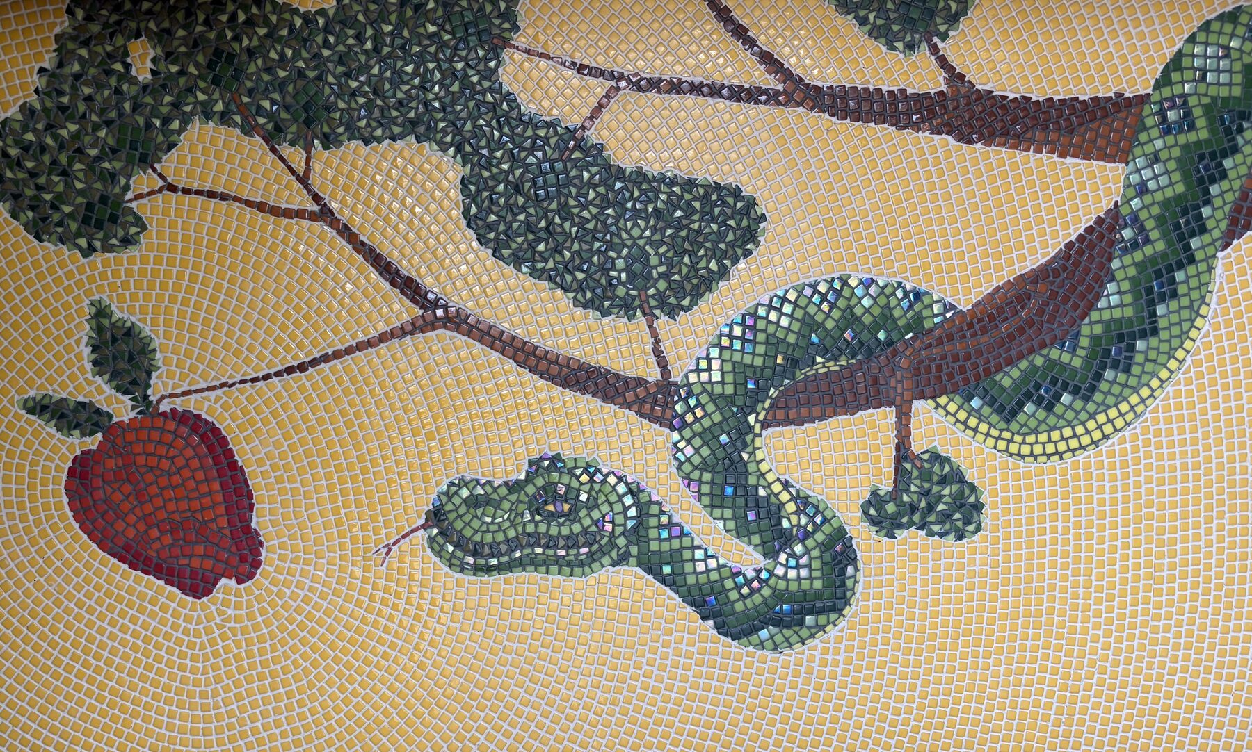 Mosaic detail of a serpent coiled around a branch with a red apple, on a yellow ground